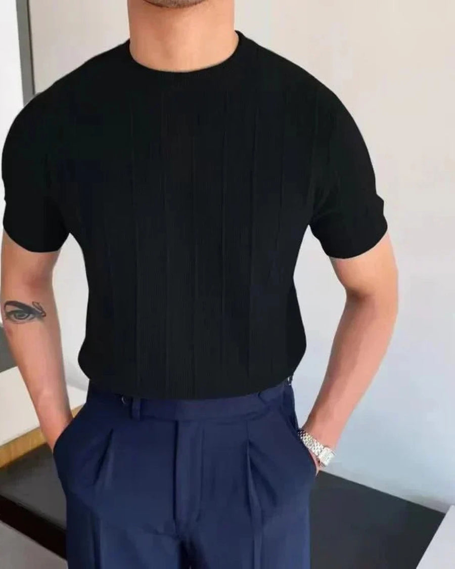 Svart ribbet t-skjorte på modell med marineblå bukser, forfra